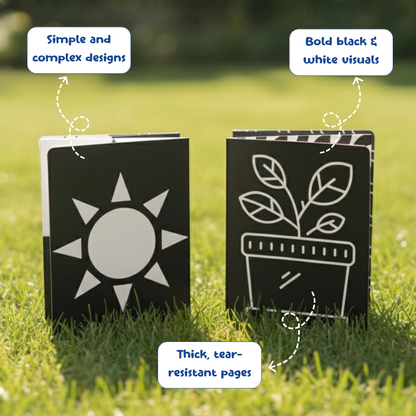 Two black books with white designs of a sun and a plant on grass