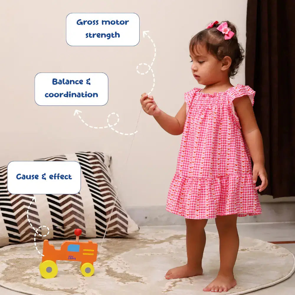 Child in a pink dress standing on a rug with educational text labels.