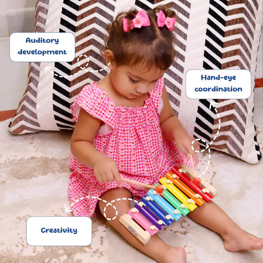 Child playing with a colorful xylophone on a carpeted floor.